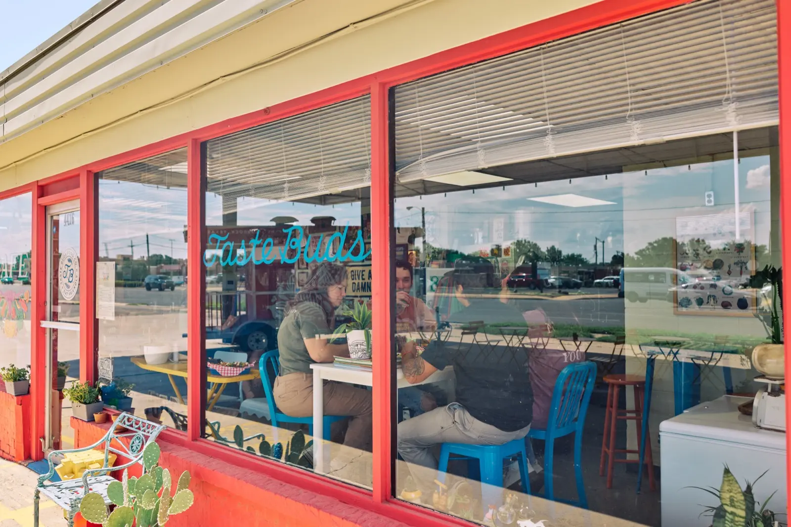 Guests eating inside the red-framed front windows, Taste Buds painted in blue script on the glass